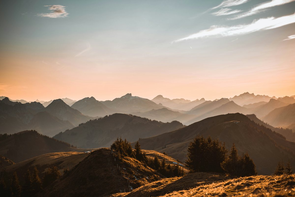 Layered mountain ridgelines receding into haze at sunset