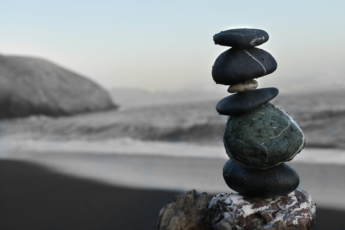 Balanced stones stacked on a shore, with the coastline soft behind
